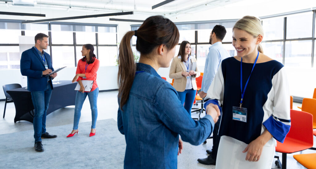 Side View Two Caucasian Businesswomen Working Bright Modern Office Standing Talking Smiling Shaking Hands With Coworkers Talking Background 1024x548